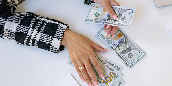 A hand counting out money on a table.