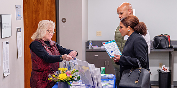 A woman sharing flyers with 2 people.
